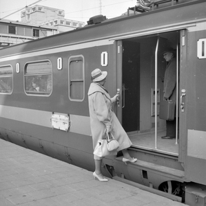 846714 Afbeelding van een vrouw die instapt in een electrisch treinstel mat. 1957 (Benelux) van de N.S. op het ...